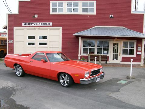 1973 Ford Ranchero - Three-quarter front view of a bright orange-red Ford Ranchero coupe-utility with a hood scoop, chrome front bumper and polished five-spoke…