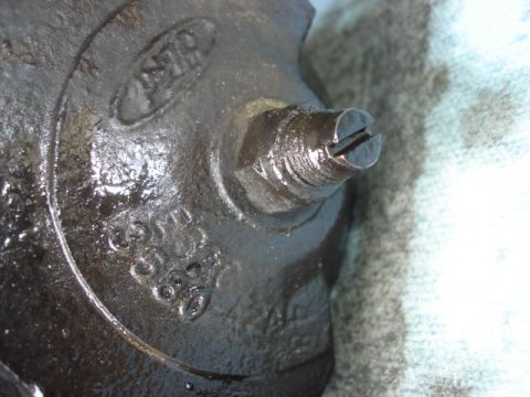 1992 Ford Bronco - This close-up shows an oily metal component with visible embossed markings and a slotted adjustment screw.