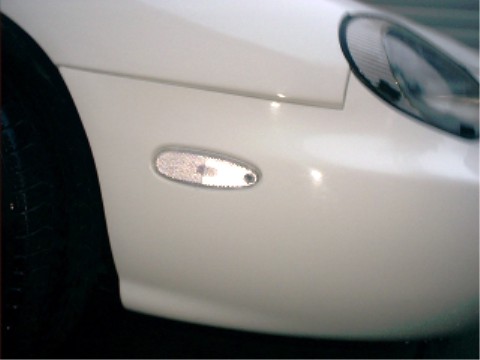 1997 Ford Taurus - Close-up of a white car's side marker light, with a portion of the black tire in the foreground.