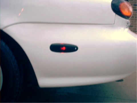 1997 Ford Taurus - Close-up of a car's front corner showing a side marker light with a red bulb illuminated.