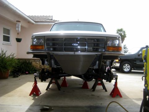 1996 Ford Bronco - The front end of a Ford truck, likely from the early to mid-1990s, is elevated on jack stands for maintenance.
