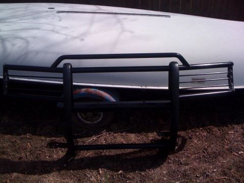 1995 Ford Bronco - Bull bar attached to the front of a white vehicle, with a rusty wheel visible.