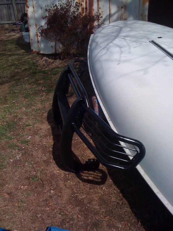 White Ford Bronco with black brush guard on front. Parked outside near a shed