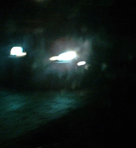 1997 Ford Taurus - The photo shows blurred vehicle lights at night, with some green reflections on the dark road surface.