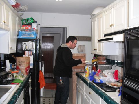 1991 Ford Bronco - A man stands in a cluttered kitchen, holding a plate.