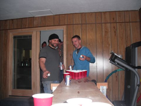 1991 Ford Bronco - Two men are engaged in a game of beer pong, with red cups and ping pong balls set up on a table.