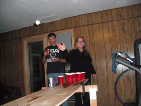 1991 Ford Bronco - Two people are playing beer pong in a room with wood-paneled walls.