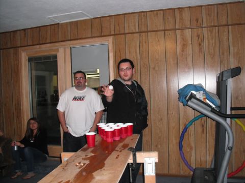 1991 Ford Bronco - People gathered for a game of beer pong in a room with wood-paneled walls and a treadmill.
