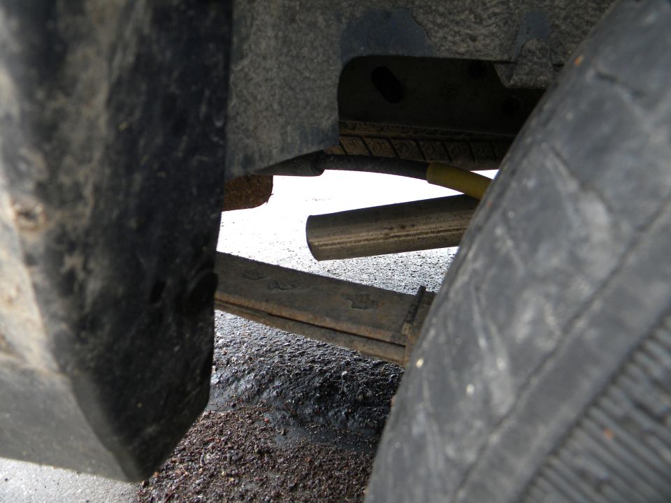 Vehicle undercarriage showing leaf springs and tire, with Supermotors logo