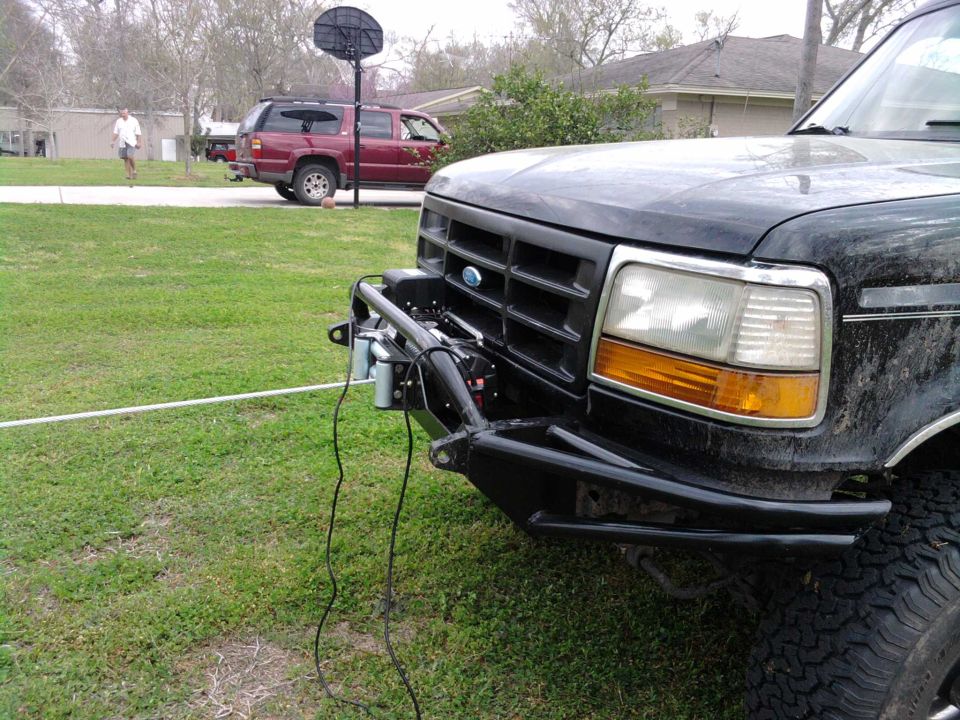 1994 Ford Bronco front end with aftermarket bumper and winch, red SUV in background