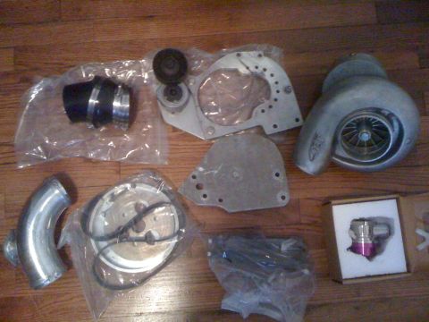 1995 Ford Bronco - Various automotive performance parts, including a turbocharger and intake components, are displayed on a wooden surface.