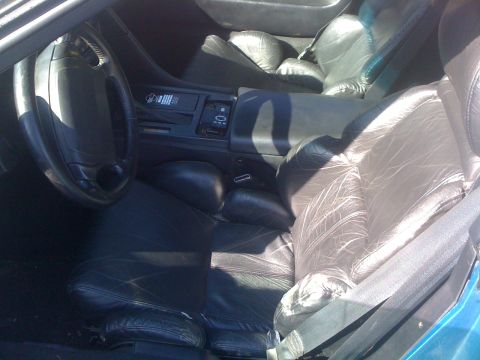 1995 Ford Bronco - Interior view of a car's dashboard and seats, showing black leather upholstery.