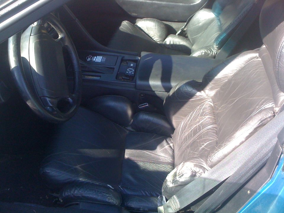 Black leather car interior with a steering wheel, dashboard, and seats visible