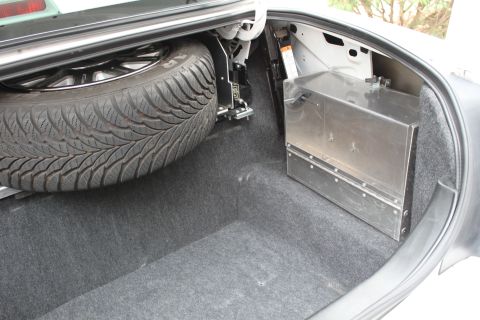 2003 Ford Crown Victoria - The trunk of a vehicle contains a spare tire and a custom metal storage box.