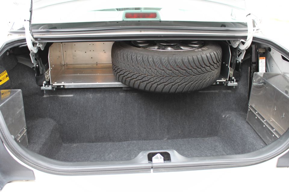 Sedan trunk with upright full-size spare wheel and bolted aluminum equipment trays