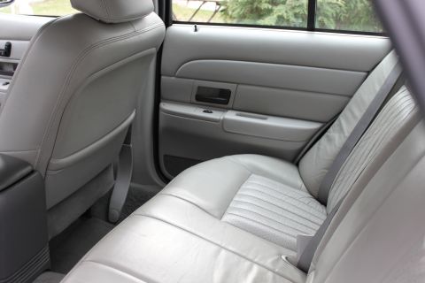 2003 Ford Crown Victoria - Interior view of the rear passenger area, showing gray leather seats and door panel details.