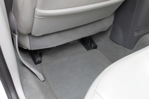 2003 Ford Crown Victoria - The image shows the floor area of a car's interior, focusing on the carpet and seat mounting hardware.