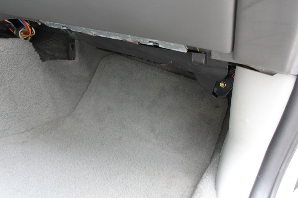Car interior showing exposed wiring under dashboard carpet