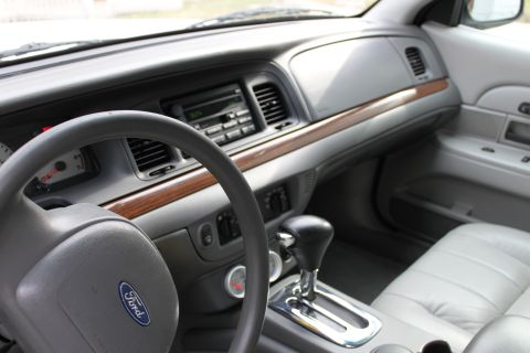 2003 Ford Crown Victoria - The interior of a 2003 Ford Crown Victoria features a wood-grain trim on the dashboard and a light-colored leather seat.