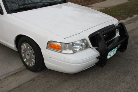 2003 Ford Crown Victoria - Front end of a white 2003 Ford Crown Victoria, equipped with a push bar and showing its distinctive grille and headlights.