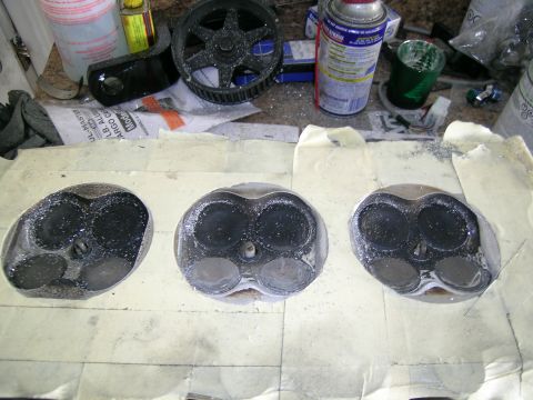 1995 Ford Probe - Engine cylinder heads covered in carbon and debris sit on a taped surface next to automotive parts and supplies.