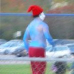 1991 Ford Bronco - A person in a red hat and blue body paint walks past a row of parked vehicles in the background.