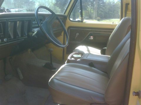 1978 Ford Bronco - The interior of a vintage Ford Bronco features tan seats and a brown dashboard with a large steering wheel.