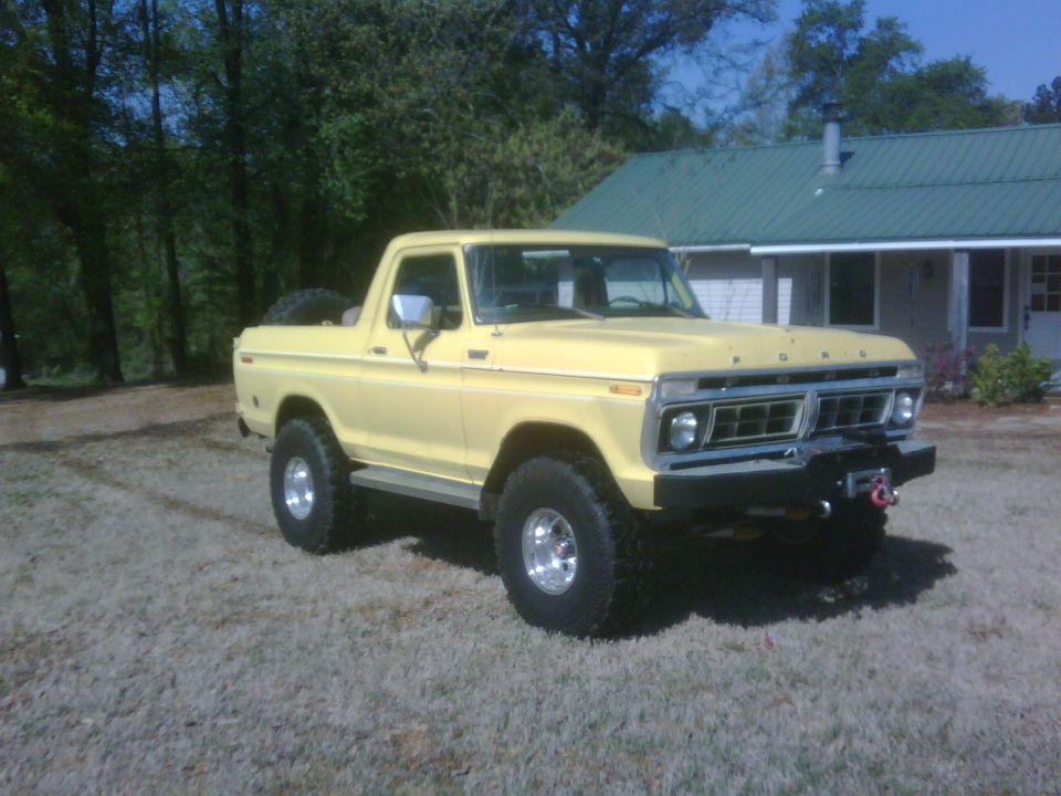 Yellow 1978 Ford Bronco with a winch on the front bumper, parked on a grassy area