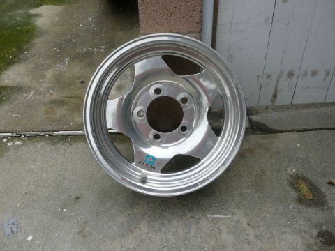 1988 Ford Bronco - An Alcoa aluminum wheel with a blue logo is shown, resting on a concrete surface.
