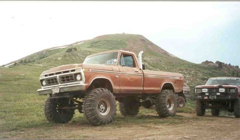 2002 Ford F-350 - A lifted 1973 Ford pickup truck is shown with another vehicle behind it on a grassy, mountainous terrain.