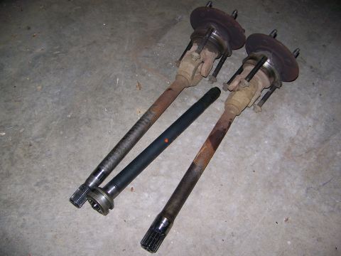 2001 Dodge 1500 - Drive axles and hubs for a vehicle are laid out on a concrete surface.
