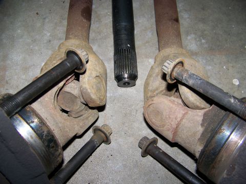 2001 Dodge 1500 - Several rusty driveshaft components are laid out on a concrete floor, ready for repair or replacement.