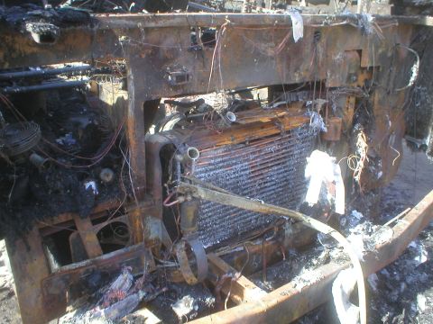 1998 GMC Sierra 3500 - Engine bay of a vehicle after a fire, showing extensive damage to the radiator and surrounding components.