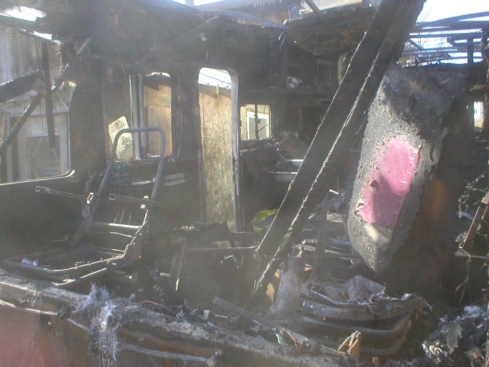 Interior of a vehicle after a fire, showing extensive damage and charred remains