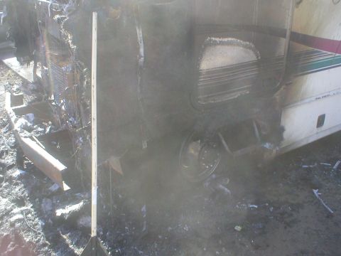 1998 GMC Sierra 3500 - This RV shows extensive fire damage, with the side heavily charred and melted.