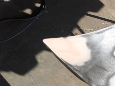 1980 Chevrolet Camaro - A car fender corner, prepped with primer and filler, sits on a cracked concrete surface.