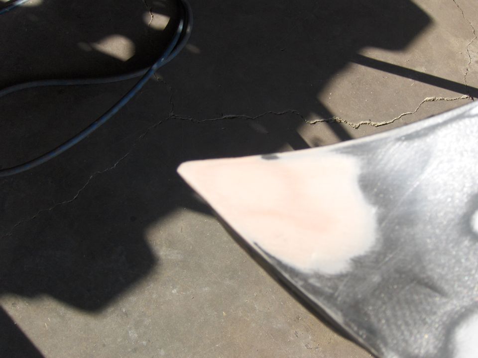 Car fender corner with primer and body filler, on cracked concrete
