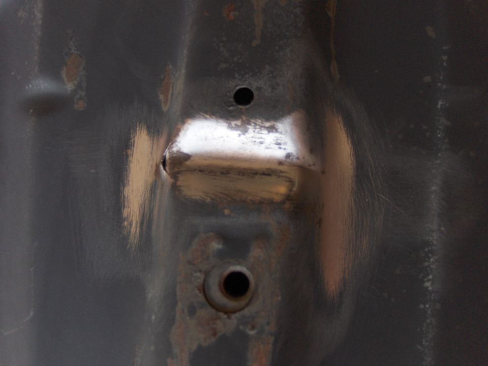 Close-up of rusted metal with two holes, one with a shiny metal insert