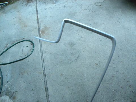 1995 Ford Bronco - A bent metal rod lies on a concrete surface next to a green hose.