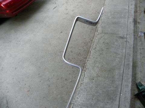 1995 Ford Bronco - A bent metal bar with a sticker is shown on a concrete surface, with a portion of a red vehicle visible.