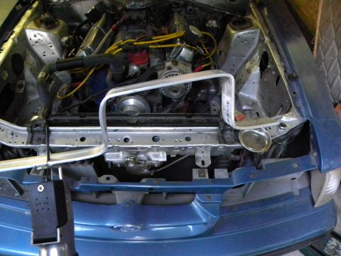 1995 Ford Bronco - Engine bay of a blue Ford vehicle, showing the engine, radiator, and front end structure.