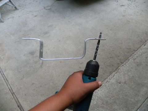 1995 Ford Bronco - A metal bracket is being drilled with a drill bit.