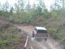 1978 Ford Bronco - A vehicle drives down a muddy, wooded path, kicking up dust.