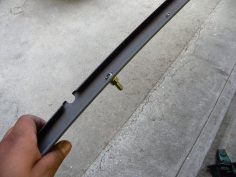 1995 Ford Bronco - Metal bracket with a brass bolt is held up for inspection.