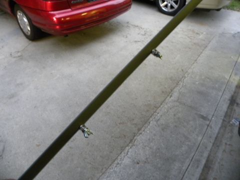 1995 Ford Bronco - A dark green metal bar with wing nuts is shown in front of a red car and a vehicle with a silver wheel.