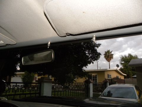 1995 Ford Bronco - View from inside a vehicle looking out at a residential scene with a palm tree under a cloudy sky.