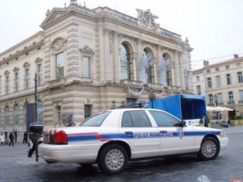 1991 Ford Crown Victoria - A 1991 Ford Crown Victoria police car, marked 'POLICE MUNICIPALE', is parked on a street in front of an ornate building.