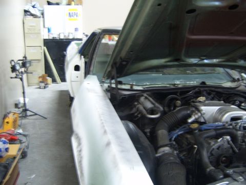 1973 Ford Ranchero - The engine bay and front fender of a car are visible, with the hood open, in what appears to be a workshop.