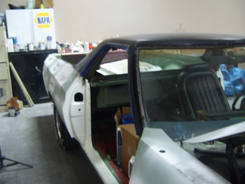 1973 Ford Ranchero - A car in a workshop with its door open, undergoing repairs or restoration.