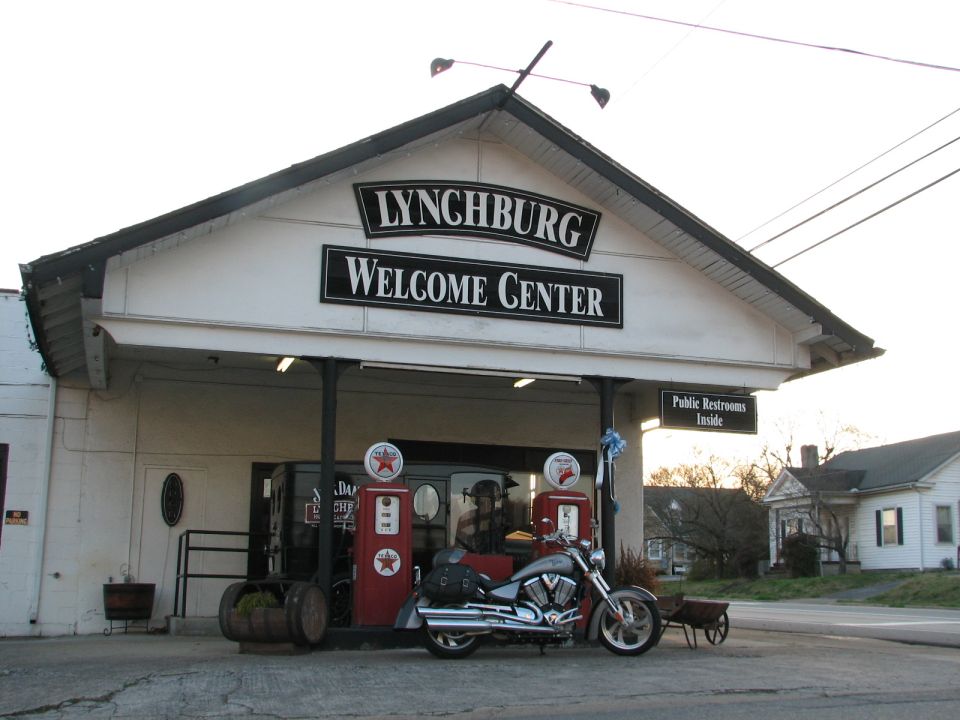 Silver 2006 Victory Kingpin motorcycle parked at a welcome center with vintage gas pumps
